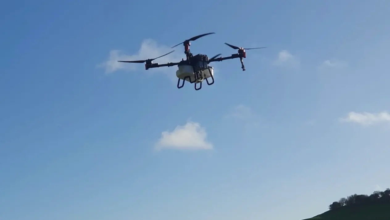 Agricultural drone flying high over an arable field for cover crop seeding
